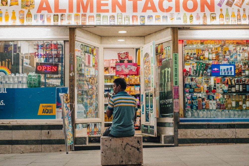 Colorful newsstand with a man sitting behind the counter.